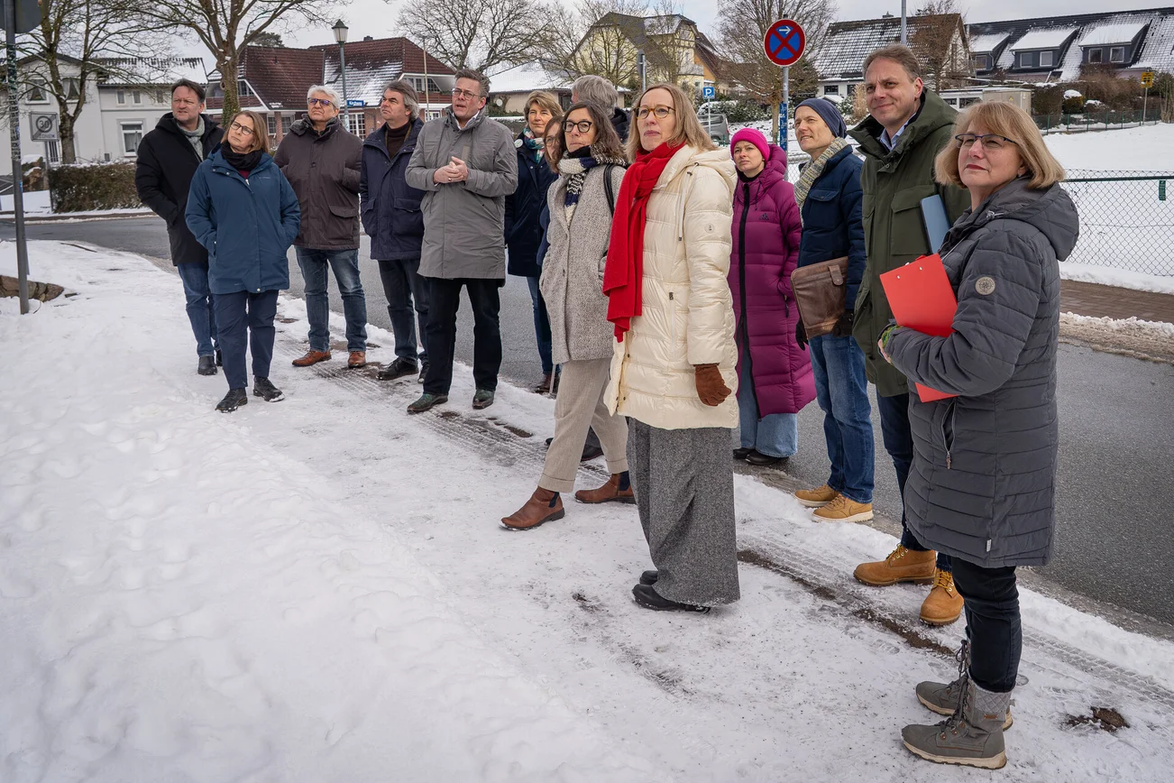 Mehrere Personen stehen im Schnee und blicken in die gleiche Richtung.
