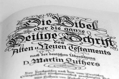 Text schwarz-weiß in altdeutscher Schrift: 'Die Bibel oder die ganze Heilige Schrift des Alten u. Neuen Testaments und der deutschen Übersetzung D. Martin Luthers' - Copyright: Ev.-Luth. Kirchenkreis Lübeck-Lauenburg
