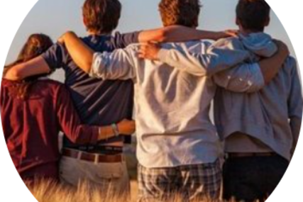 Jugendliche im Schulterschluss.  Man sieht sie von hinten in einem Feld stehen.
