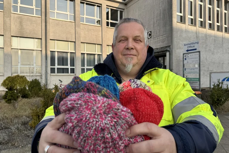 Ein Mann hält Mützen in der Hand 