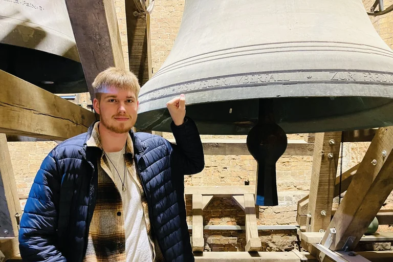 Ein junger Mann steht vor der großen Glocke der Marienkirche.